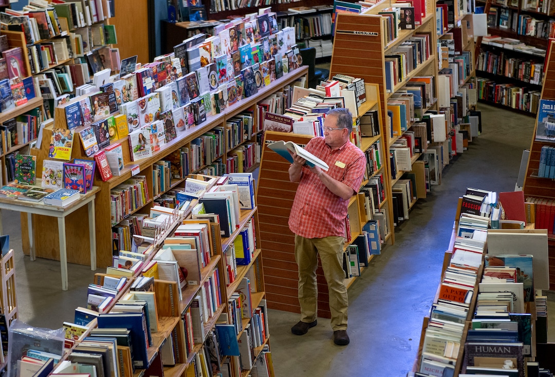 (Leah Hogsten  |  The Salt Lake Tribune)  Gary Teare of Salt Lake City thumbs through a potential book to buy on the floor of Weller Book Works, August 7, 2019. Weller Book Works — formerly Zion Bookstore and Sam Weller's Books — is celebrating its 90th year.