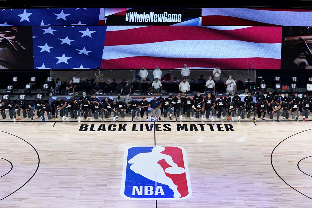 (Ashley Landis | AP) Members of the New Orleans Pelicans and Utah Jazz kneel together around the Black Lives Matter logo on the court during the national anthem before the start of an NBA basketball game Thursday, July 30, 2020, in Lake Buena Vista, Fla.