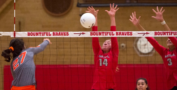(Rick Egan  |  The Salt Lake Tribune)  Naomi Pulu (27), Skyridge, hits the ball as  Hannah Howard (3), and Bri Mortensen, (14), defined for Bountiful, in volleyball action, Bountiful vs. Skyridge, at Bountiful High, Wednesday, September 6, 2017.
