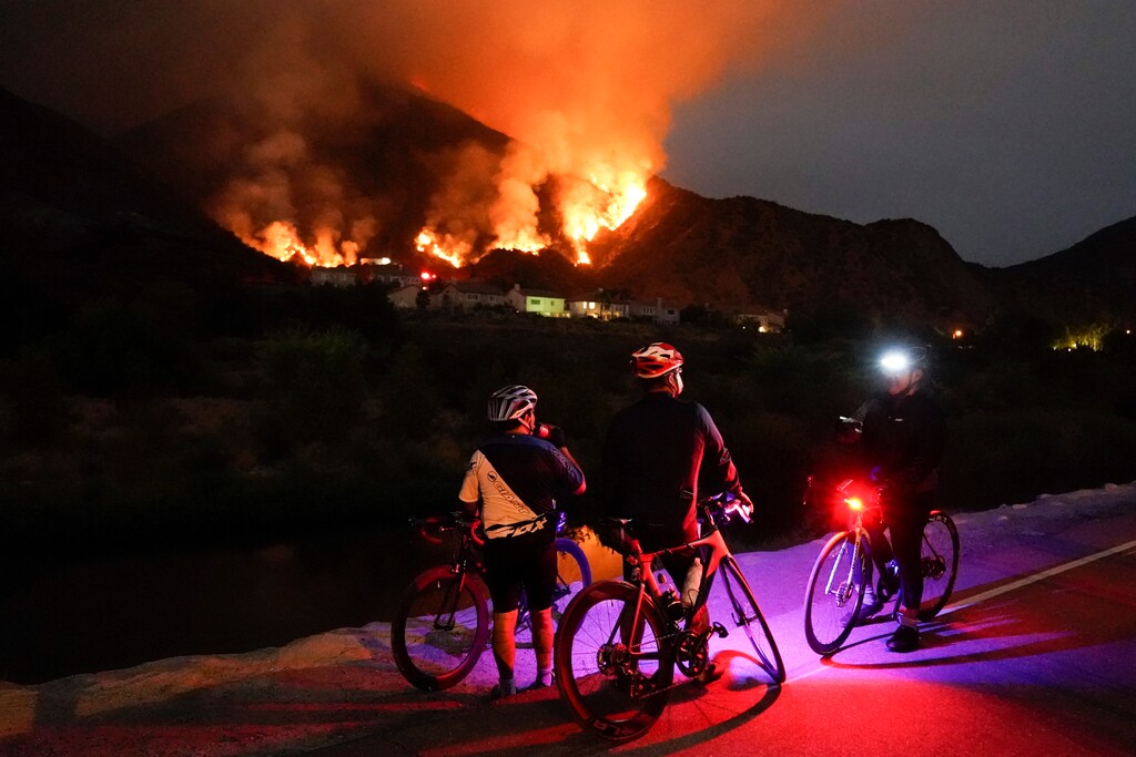 (Marcio Jose Sanchez | AP) Cyclists rest along a trail as the Ranch Fire burns, Thursday, Aug. 13, 2020, in Azusa, Calif. Heat wave conditions were making difficult work for fire crews battling brush fires and wildfires across Southern California.