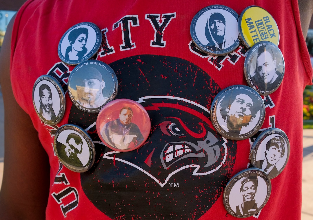 (Leah Hogsten  |  The Salt Lake Tribune) A protester wears pins of people who have been killed by police in Utah. About 75 people rallied for the People's Council to defund the West Valley Police Department outside West Valley City Hall, Aug.8, 2020.  Saturday's rally was hosted by the Salt Lake chapter of the Party for Socialism and Liberation.