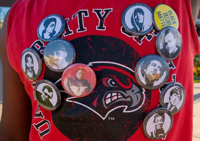 (Leah Hogsten  |  The Salt Lake Tribune) A protester wears pins of people who have been killed by police in Utah. About 75 people rallied for the People's Council to defund the West Valley Police Department outside West Valley City Hall, Aug.8, 2020.  Saturday's rally was hosted by the Salt Lake chapter of the Party for Socialism and Liberation.