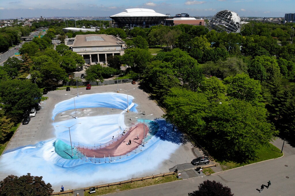 (Seth Wenig | AP) Artist Jorge Rodriguez-Gerada works on a 20,000 square foot mural of a healthcare worker near the Queens Museum, back left, and the USTA Billie Jean King National Tennis Center, back center, in the Queens borough of New York, Wednesday, May 27, 2020. The mural is to honor those who lost their lives during the coronavirus pandemic, especially minority healthcare workers. The portrait was inspired by Dr. Ydelfonso Decoo, an immigrant doctor who died from coronavirus complications while serving hard-hit communities of color.