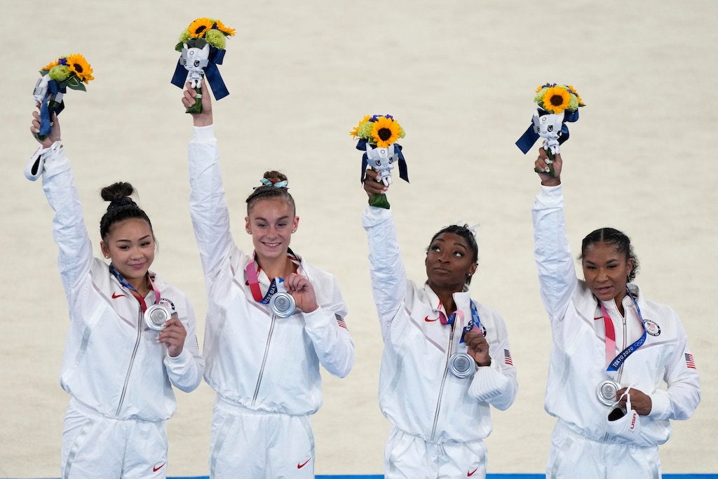 (Natacha Pisarenko | AP) United States' artistic gymnastics women's team members, from left, Sunisa Lee, Grace McCallum, Simone Biles and Jordan Chiles celebrate on the podium after winning the silver medal in the artistic women's team the 2020 Summer Olympics, Tuesday, July 27, 2021, in Tokyo.
