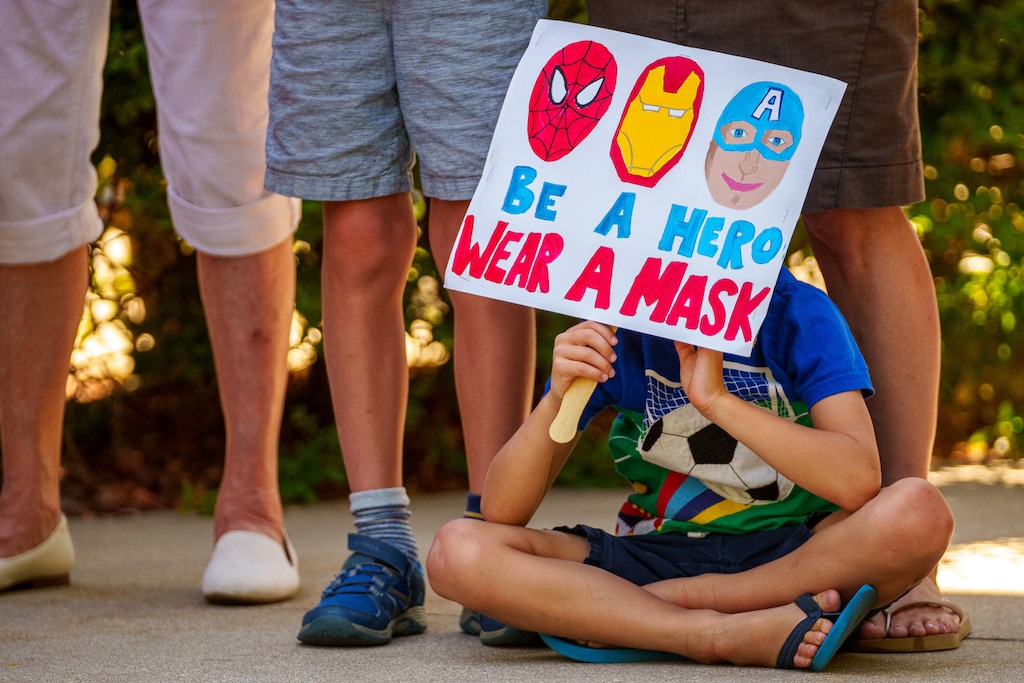 (Trent Nelson | The Salt Lake Tribune) Jack Nazzaro sits at his mother's feet as speakers react to the county's vote against a mask mandate in schools on Thursday, Aug. 12, 2021.