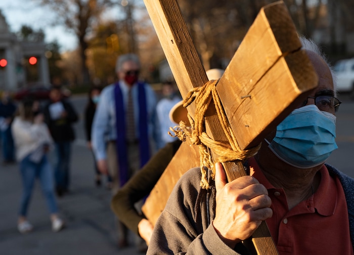 (Francisco Kjolseth | The Salt Lake Tribune) Anthony Estrada takes a turn carrying the cross as mask wearing Utah Christians walk the streets of Salt Lake City beginning at Cathedral of the Madeleine on Good Friday, to symbolically mark Jesus' carrying the cross to his crucifixion, April 2, 2021.