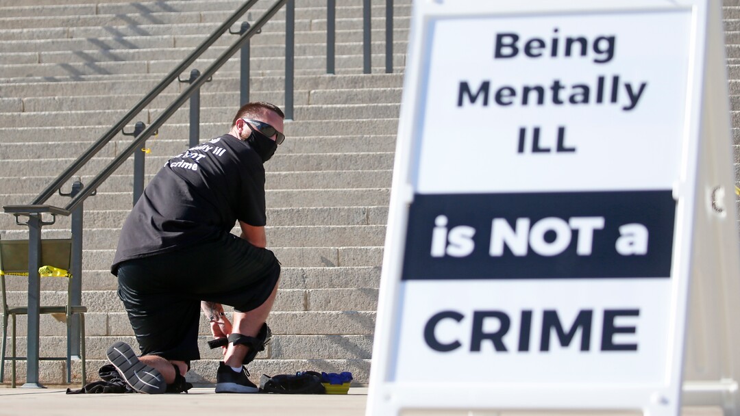 Shane Brooks, a Marine Corps veteran, kneels for nine hours outside the Utah Capitol to call attention to racial injustice, police brutality and mental health, Thursday, Aug. 6, 2020, in Salt Lake City. Brooks said people of color with mental illness are "looked at as if they have already committed a crime" and some end up dead in encounters with police, KTVX-TV reported. Brooks said his marathon silent protest was inspired by Bobby Duckworth, a 26-year-old who was shot and killed in 2019 by police responding to a report of a suicidal person in Wellington, Utah. (AP Photo/Rick Bowmer)
