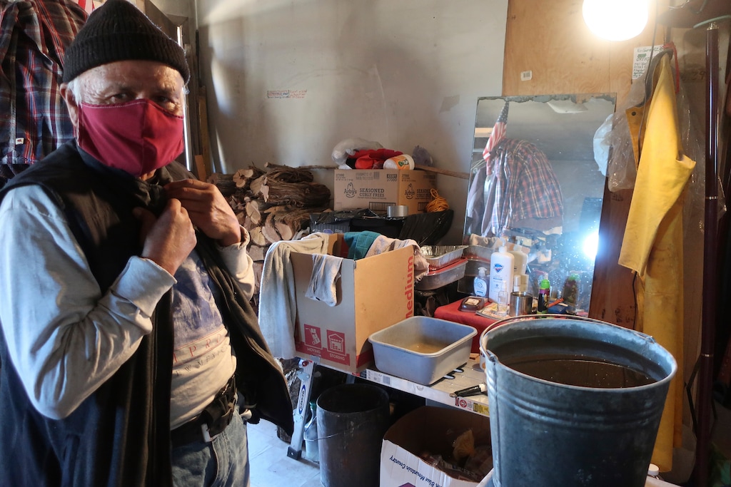 (Felicia Fonseca | The Associated Press) Raymond Clark stands in front of his makeshift washing station in his home in Teesto, Arizona, on the Navajo Nation on Thursday, Feb. 11, 2021. Teesto workers, health representatives, volunteers and neighbors keep close tabs on another to ensure the most vulnerable citizens get the help they need.