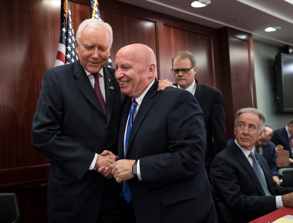 House Ways and Means Committee Chairman Kevin Brady, R-Texas, center, embraces Senate Finance Committee Chairman Orrin Hatch, R-Utah, left, as House and Senate conferees after GOP leaders announced they have forged an agreement on a sweeping overhaul of the nation's tax laws, on Capitol Hill in Washington, Wednesday, Dec. 13, 2017. Rep. Richard Neal, D-Mass., ranking member of the House Ways and Means Committee, looks on at far right. Democrats objected to the bill and asked that a final vote be delayed until Senator-elect Doug Jones of Alabama is seated. (AP Photo/J. Scott Applewhite)