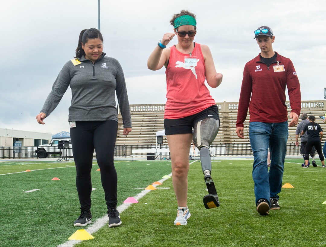 (Rick Egan  |  The Salt Lake Tribune)     Grace Ku helps Kaylene Baker, Helena, Mt, along with Will Cook, during the fourth annual Utah Adaptive Mobility Clinic at Skyline High school. The clinic allows anyone with "lower extremity limb loss or limb difference" or amputees without legs, to practice walking and running. Saturday, June 1, 2019.