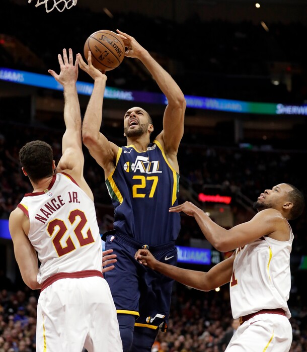 Utah Jazz's Rudy Gobert (27), from France, shoots between Cleveland Cavaliers' Larry Nance Jr. (22) and Cleveland Cavaliers' Rodney Hood (1) in the first half of an NBA basketball game, Friday, Jan. 4, 2019, in Cleveland. (AP Photo/Tony Dejak)