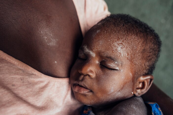 (KC Nwakalor | The New York Times) Faith Osi holds her sleeping infant daughter, Miracle, on her family's cassava farm in Obrikom, in the heart of Nigeria's oil-rich delta, July 20, 2020. Around the world, the poor and marginalized are much more likely to be vulnerable to extreme heat; methane gas flares burning around the clock in Obrikom make this already hot area worse still.