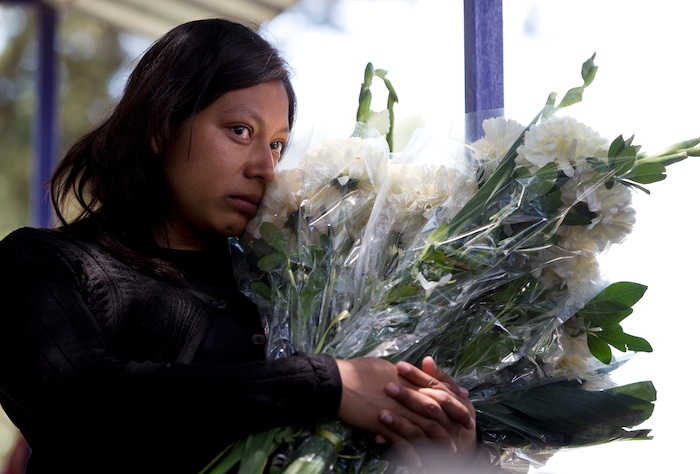 In this Aug. 18, 2017 photo, Zurisadai Sevilla, holds flowers during a graveside ceremony to place a cross, flowers, and a box of mementos for her slain sister Jessica Sevilla, 29, in Villa Cuauhtemoc, Mexico state. Jessica's mutilated body was found on a highway about 20 miles (30 kilometers) from where she was last seen alive at a gas station in her red, brand-new Mazda. (AP Photo/Rebecca Blackwell)