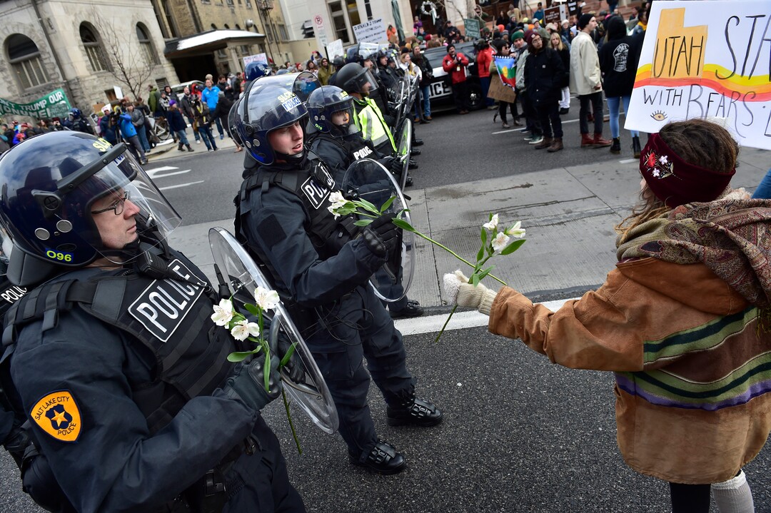(Scott Sommerdorf   |  The Salt Lake Tribune)   Reminiscent of a 1960's protest image, a woman offers flowers to SLCPD who had deployed on State Street after the protestors blocked the street near 100 South after President Trump's visit to Salt Lake City, Monday, December 4, 2017.  