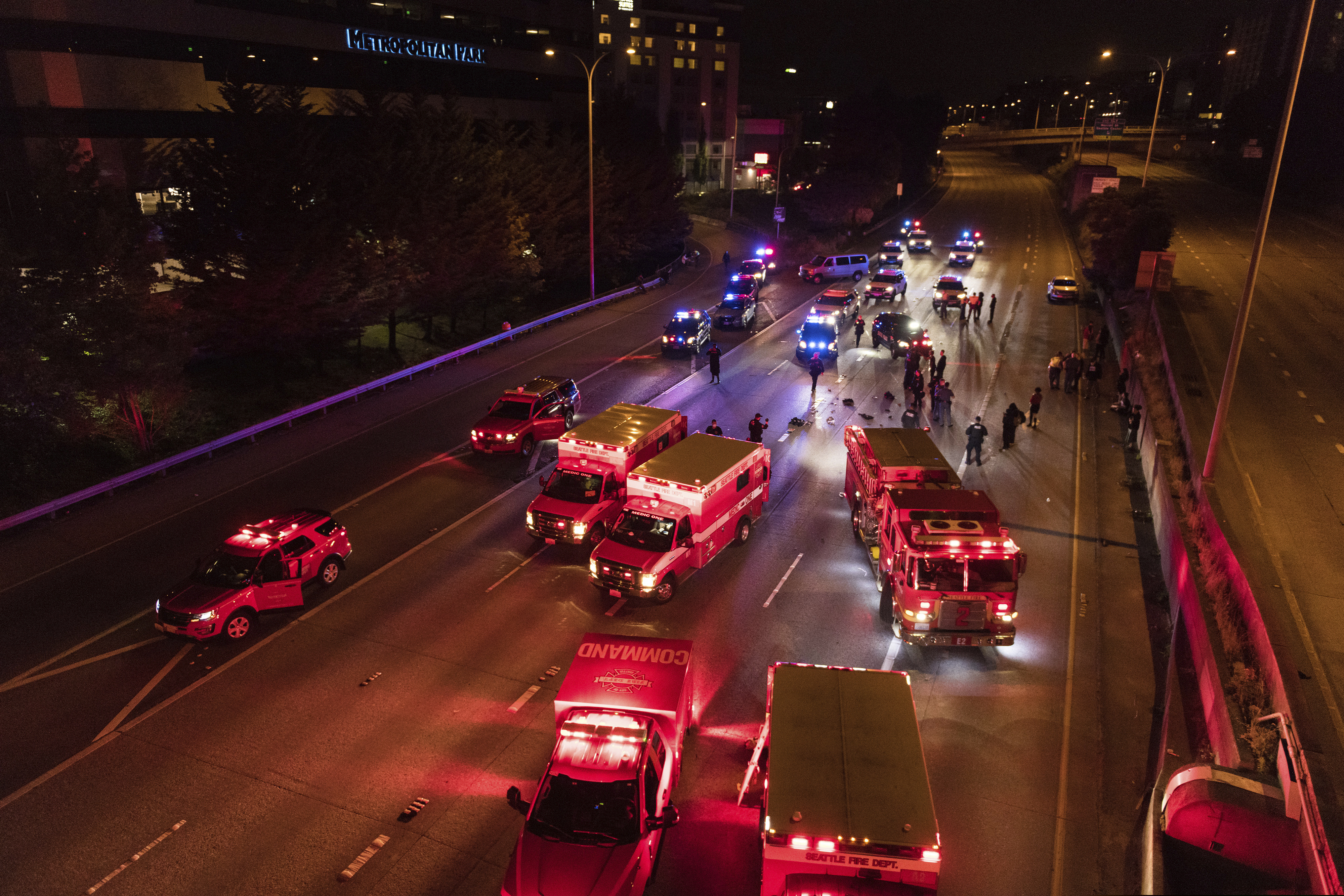 (James Anderson via The Associated Press) Emergency personnel work at the site where a driver sped through a protest-related closure on the Interstate 5 freeway in Seattle, authorities said early Saturday, July 4, 2020. Dawit Kelete, 27, has been arrested and booked on two counts of vehicular assault.
