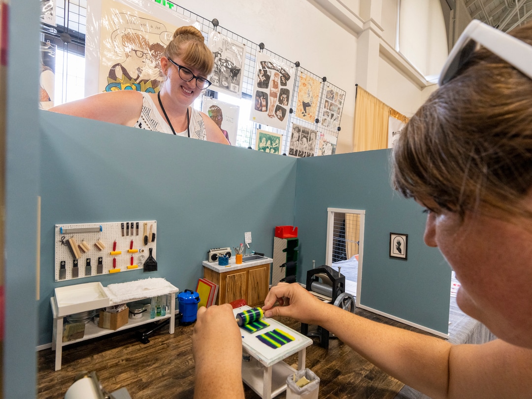 (Rick Egan | The Salt Lake Tribune) Artist Trishelle Jeffery watches as Julie Jeffery makes a mono print in a Treshelle's miniature print shop at the14th annual Craft Lake City DIY FEST, at the Fair Park, Aug. 13, 2022.