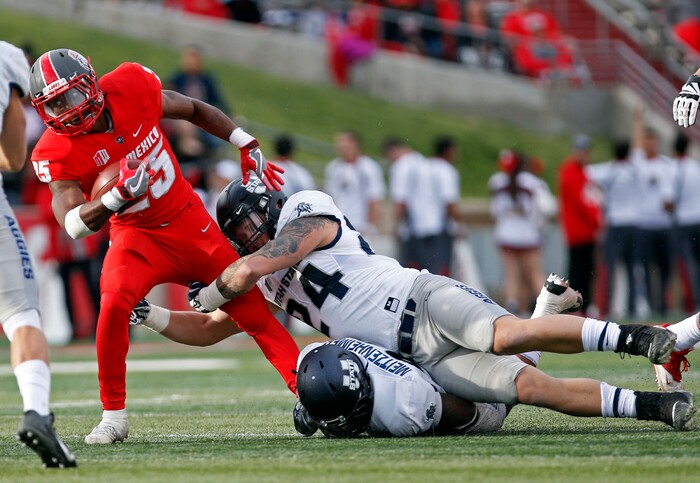 New Mexico running back Tyrone Owens (25) is stopped by Utah State linebacker Dalton Baker (24) and linebacker Kevin Meitzenheimer during the first half of an NCAA college football game in Albuquerque, N.M., Saturday, Nov. 4, 2017. (AP Photo/Andres Leighton)