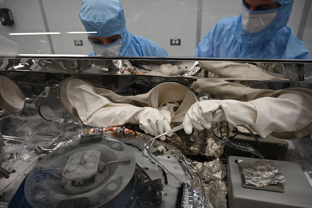 (NASA | The New York Times) In an image provided by NASA, Astromaterials processors at the Johnson Space Center in Houston collected asteroid particles from the base of the OSIRIS-REx science canister after its return from space in 2023. Scientists studying samples that NASA collected from the asteroid Bennu found a wide assortment of organic molecules that shed light on how life arose.