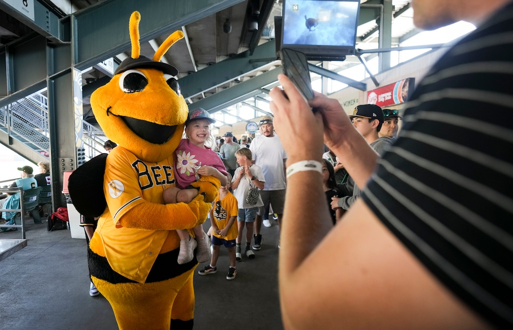 (Bethany Baker  |  The Salt Lake Tribune) Caleb Rottman takes a photo of his daughter Joanna Rottman, 4, with Bumble during the final game for the Salt Lake Bees at SmithÕs Ballpark in Salt Lake City on Sunday, Sept. 22, 2024.