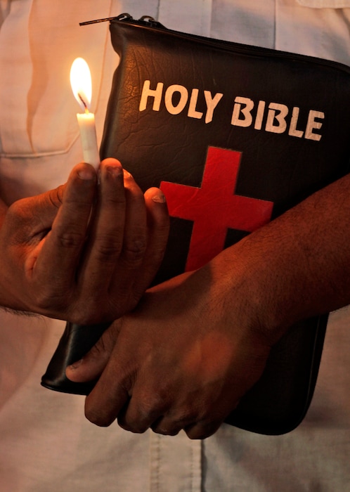 (AP Photo/Ajit Solanki) An Indian Christian holding a candle and a Bible prays at a church on Good Friday in Ahmadabad, India, Friday, April 6, 2012.