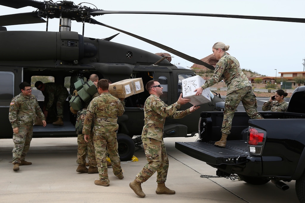 FILE - In this March 31, 2020, file photo, members of an Arizona National Guard unit pause while loading a helicopter with medical supplies to be taken to the remote Navajo Nation town of Kayenta in Phoenix. The Navajo Nation is ordering all people on the tribe's sprawling reservation to wear protective masks when out in public to help fight the spread of the coronavirus. Tribal officials announced Friday, April 17, that the Navajo Department of Health issued an emergency health order for the reservation, which includes parts of Arizona, New Mexico and Utah. (AP Photo/Ross D. Franklin, File)
