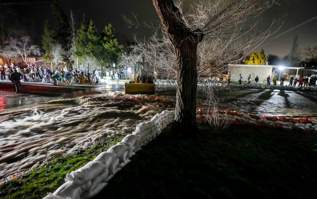 (Francisco Kjolseth | The Salt Lake Tribune) People work to protect homes into the night along 1700 South in Salt Lake City from the rising flow of Emigration Creek through Wasatch Hollow Park on Wednesday, April 12, 2023. 