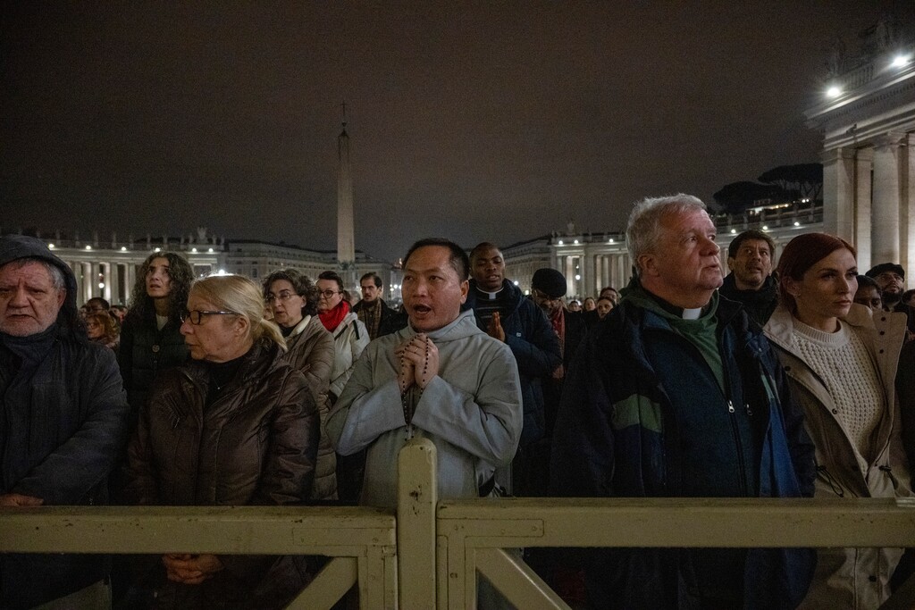(James Hill | The New York Times) Clergy and the public take part in a recitation of the rosary for Pope Francis’ health at St. Peter’s Square in Vatican City, on Monday night, Feb. 24, 2025. The pontiff suffered a respiratory setback Friday.