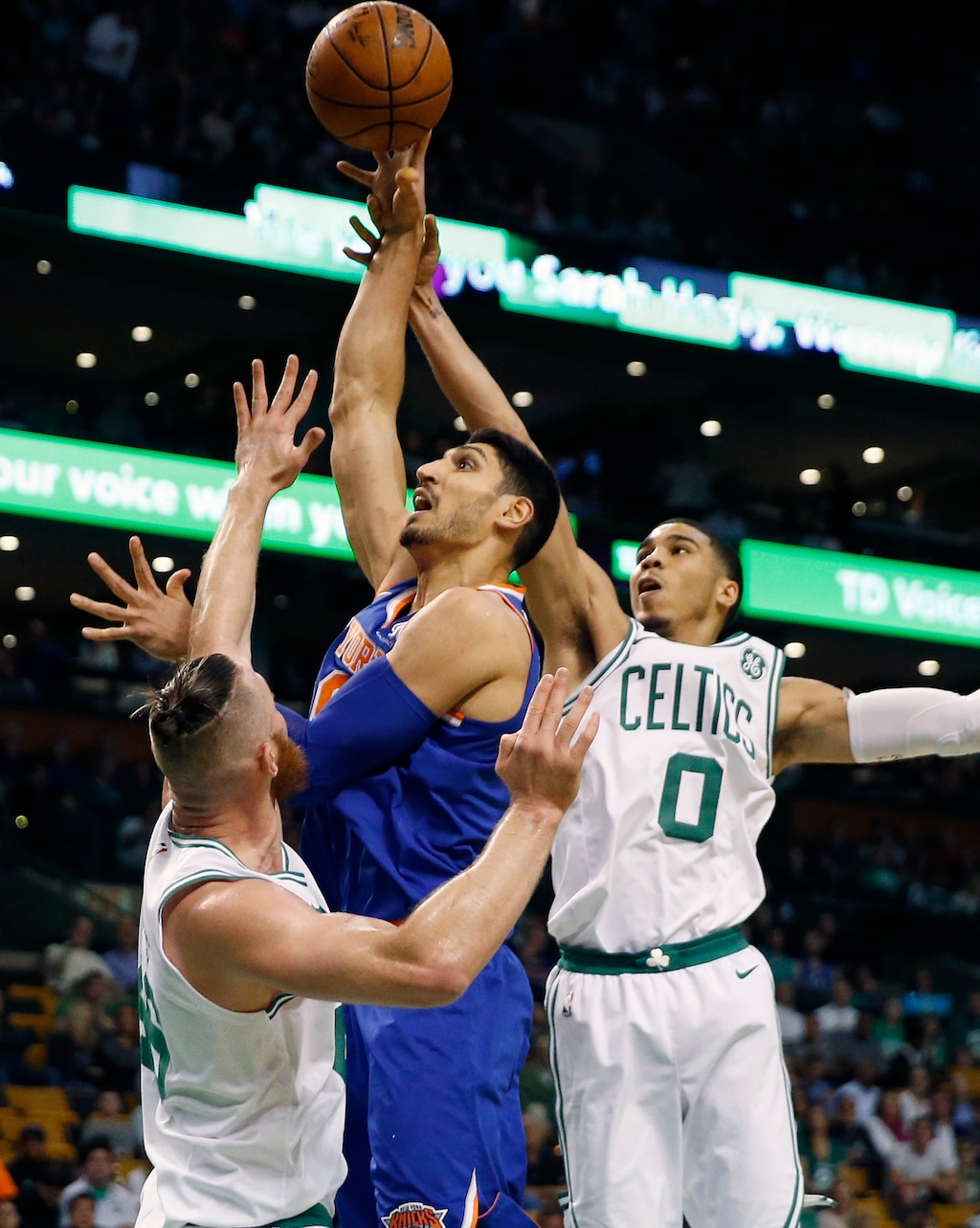 New York Knicks' Enes Kanter, center, shoots against Boston Celtics' Aron Baynes, left, and Jayson Tatum (0) during the first quarter of an NBA basketball game in Boston, Tuesday, Oct. 24, 2017. (AP Photo/Michael Dwyer)
