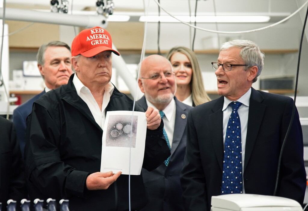 (Hyosub Shin | Atlanta Journal-Constitution | AP) President Donald Trump holds a photograph of coronavirus as Dr. Steve Monroe, right, with CDC speaks to members of the press at the headquarters of the Centers for Disease Control and Prevention in Atlanta on Friday, March 6, 2020.