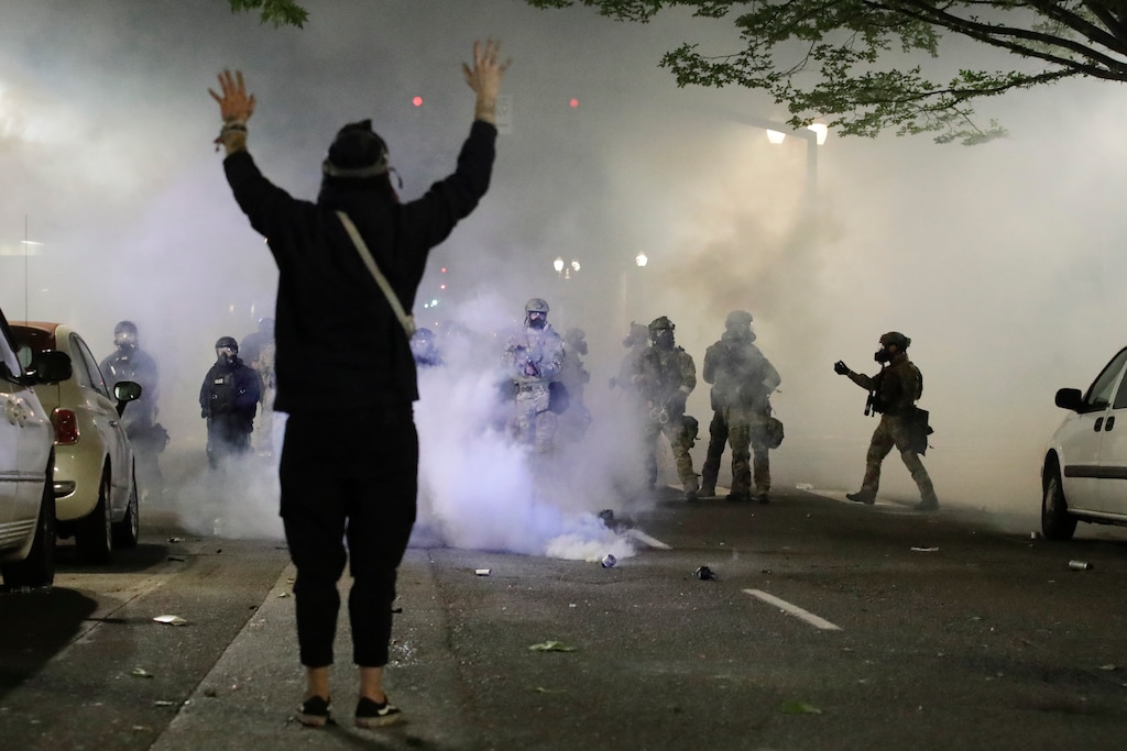 (Marcio Jose Sanchez | AP file photo)  A demonstrator stands in front of federal officers during a Black Lives Matter protest at the Mark O. Hatfield United States Courthouse Friday, July 24, 2020, in Portland, Ore.