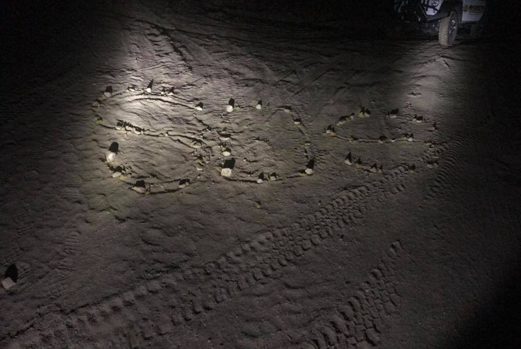 An elderly Texas man built an "S.O.S." of rocks and flowers. It was spotted by helicopter, leading to his rescue. His wife had been found hours earlier, lying on a remote mountain road where she had tried to walk for help. (Photo courtesy Kane County Sheriff's Office)