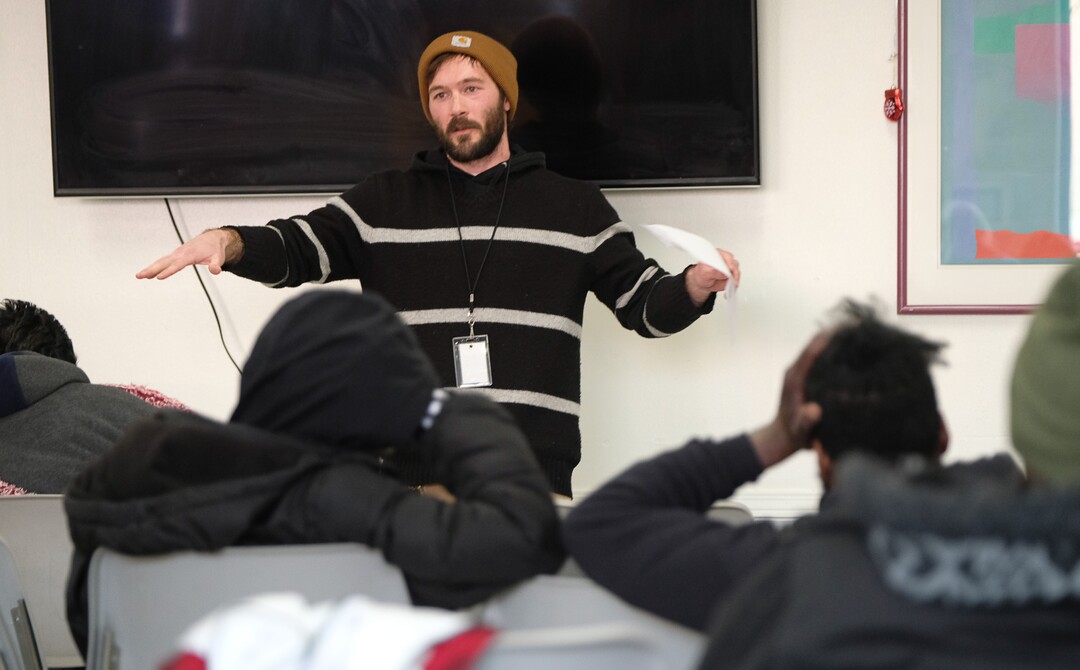 (Francisco Kjolseth  |  The Salt Lake Tribune) Joe Pace, Employment and Life Skills Coordinator leads a town hall meeting in the day room of the Weigand Center on Wednesday, Dec. 18, 2019, where Catholic Community Services hosts the weekly event to get more input from its homeless clients. In the back of the room there is a survey kiosk that asks clients about service, cleanliness and what people would like to see to better serve them.