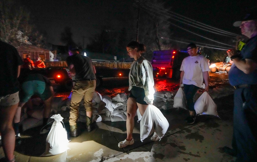 (Francisco Kjolseth | The Salt Lake Tribune) People work to protect homes into the night along 1700 South in Salt Lake City from the rising flow of Emigration Creek through Wasatch Hollow Park on Wednesday, April 12, 2023. 