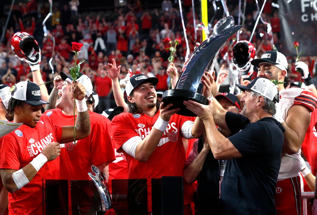 (Steve Marcus | AP) Utah coach Kyle Whittingham, right, hands the trophy to quarterback Cameron Rising, center, after Utah defeated Southern California 47-24 in the Pac-12 Conference championship NCAA college football game Friday, Dec. 2, 2022, in Las Vegas.