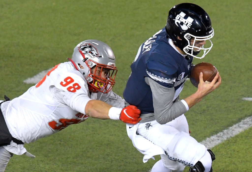 Utah State quarterback Andrew Peasley (6) scrambles away from New Mexico defensive end Joey Noble (98) during the first half of an NCAA college football game Thursday, Nov. 26, 2020, in Logan, Utah. (Eli Lucero/Herald Journal via AP)