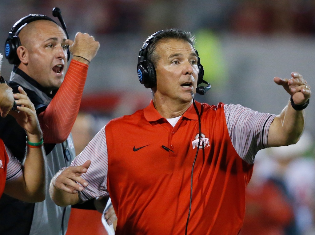 FILE - In this Sept. 17, 2016, file photo, Ohio State head coach Urban Meyer, right, and then-assistant coach Zach Smith, left, gesture from the sidelines during an NCAA college football game against Oklahoma in Norman, Okla. Ohio State expects to open fall camp as scheduled on Friday, Aug. 3, 2018, but without coach Urban Meyer.  Meyer was put on administrative leave on Wednesday, Aug. 1 over the handling of a longtime assistant who has been accused of domestic violence. Co-offensive coordinator Ryan Day will be running the team while Ohio State investigates claims that Meyer’s wife knew about 2015 allegations of abuse against former Buckeyes assistant Zach Smith, who was fired last week. (AP Photo/Sue Ogrocki, File)