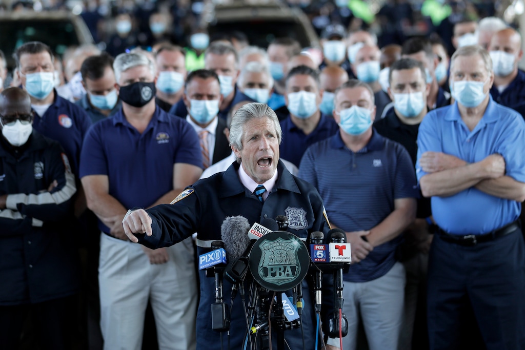 Surrounded by law enforcement and supporters, New York City Police Benevolent Association President Pat Lynch, center, speaks during a news conference in New York, Tuesday, June 9, 2020. A New York City police officer who was caught on video violently shoving a woman to the ground during a protest over the death of George Floyd was charged Tuesday with assault and other counts, prosecutors announced. Lynch said the mayor and police leaders were "sacrificing cops to save their own skin" by sending officers out to protests with "no support and no clear plan." (AP Photo/Seth Wenig)