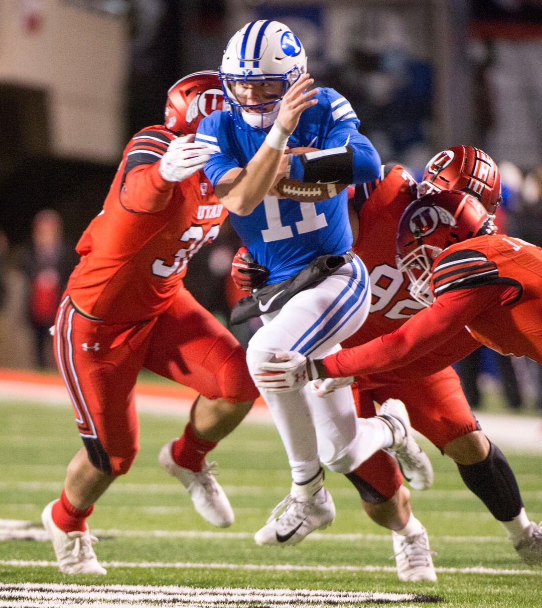 (Rick Egan  |  The Salt Lake Tribune)      Brigham Young Cougars quarterback Zach Wilson (11) drags three Ute defenders with him, as he runs the ball for the Cougars, in football action between the Brigham Young Cougars and the Utah Utes, at Rice-Eccles Stadium, Saturday, November 24, 2018.
