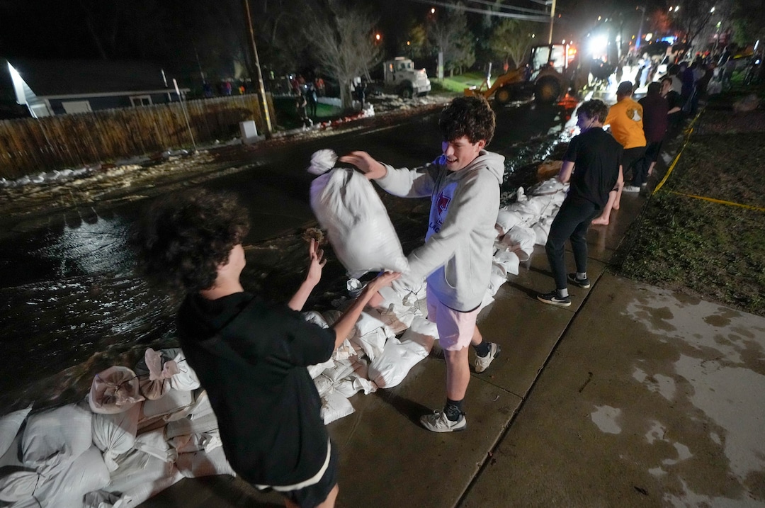 (Francisco Kjolseth | The Salt Lake Tribune) Will Fagergren, left, and Andrew Williams help with the sandbag line as they help protect homes into the night along 1700 South in Salt Lake City from the rising flow of Emigration Creek through Wasatch Hollow Park on Wednesday, April 12, 2023. 