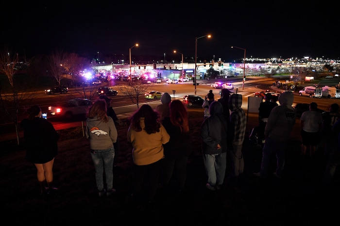 People stand across the street from a shooting investigation at a Walmart store, Wednesday, Nov. 1, 2017, in Thornton, Colo.  Several people were killed in a shooting inside a suburban Denver Walmart on Wednesday night, forcing customers to either hide in the store or frantically run for the doors. Thornton police advised people to stay away from the area as dozens of police cruisers and emergency vehicles raced to the scene. (Andy Cross/The Denver Post via AP)