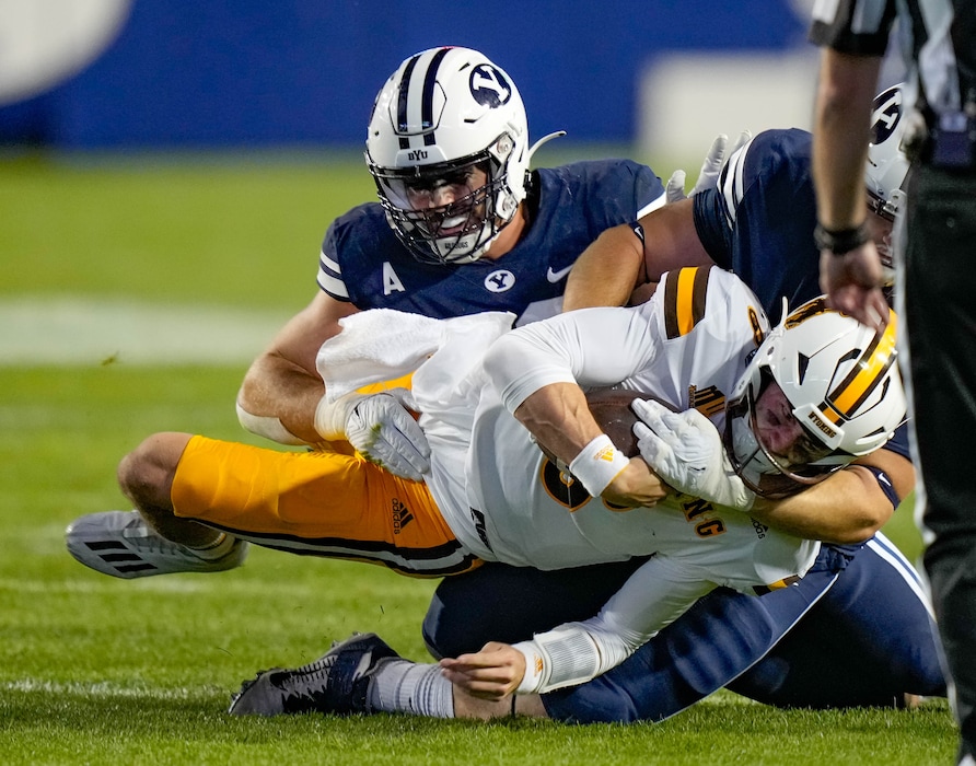 (Francisco Kjolseth | The Salt Lake Tribune) Wyoming Cowboys quarterback Andrew Peasley (6) is taken down by Brigham Young Cougars defensive lineman Tyler Batty (92) and Brigham Young Cougars defensive lineman John Nelson (94) in football action between the Brigham Young Cougars and the Wyoming Cowboys at LaVell Edwards Stadium in Provo, on Saturday, Sept. 24, 2022.