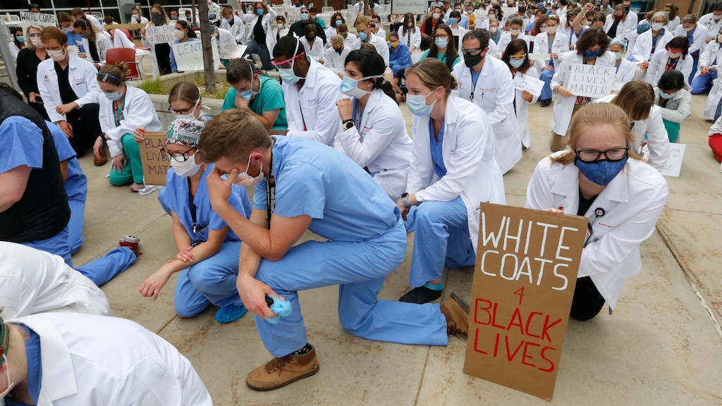 Healthcare workers and medical students pause for 8 minutes 46 seconds of silence in front of the University of Utah Health Sciences Education Building during a demonstration in support of the Black Lives Matter movement Friday, June 5, 2020, in Salt Lake City. The White Coats for Black Lives protest was organized to stand in solidarity with those speaking out against the death of George Floyd who died after being restrained by Minneapolis police officers on May 25. (AP Photo/Rick Bowmer)