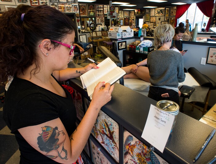 (Rick Egan | The Salt Lake Tribune) Ana Antones reads a book as she waits to get a tattoo, at the Yellow Rose Tattoo, during a flash tattoo event where all proceeds go to the Rape Recovery Center of Utah. It's part of a national event where tattoo shops raise money for sexual assault victims. Sunday, June 10, 2018.