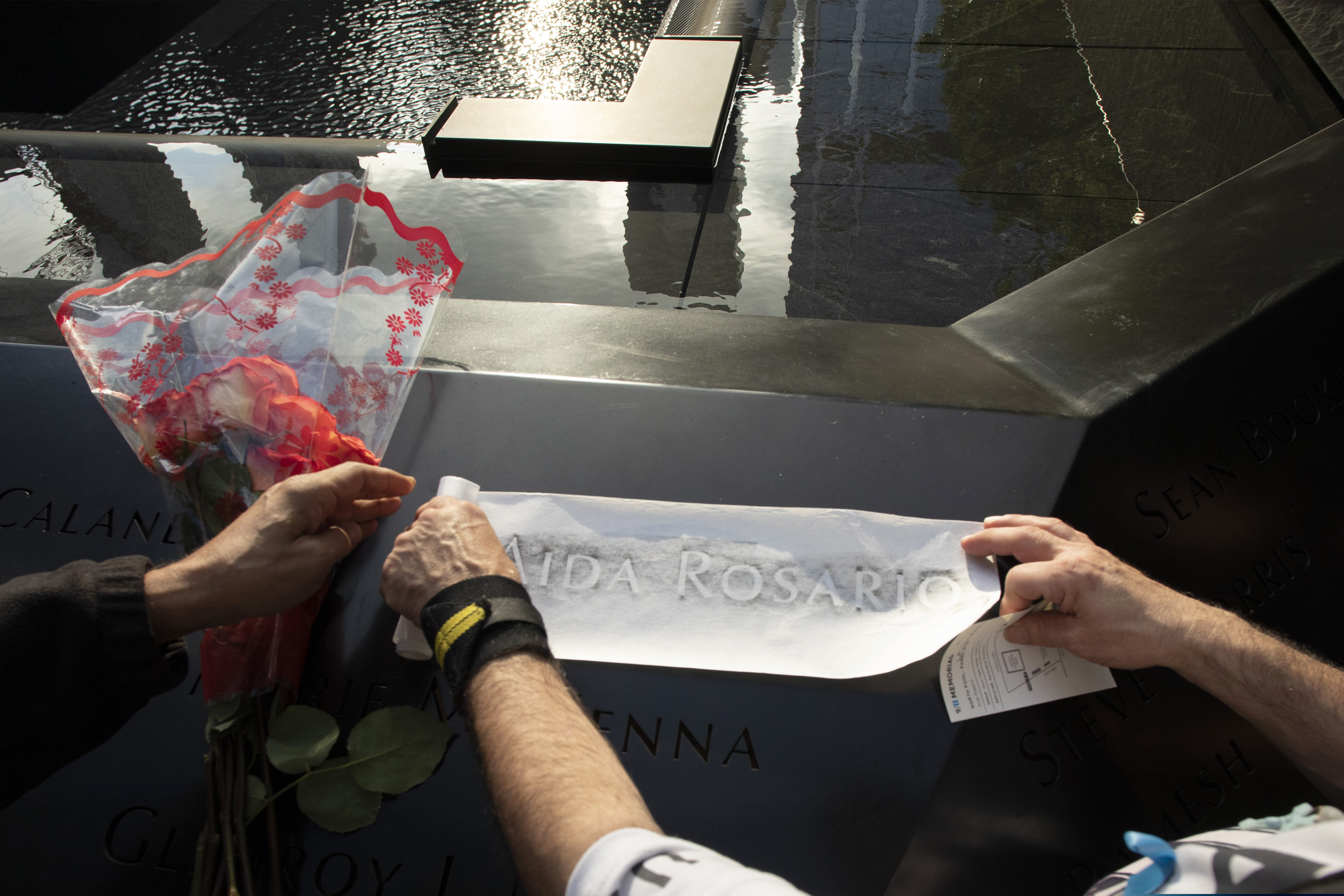 (Mark Lennihan | AP Photo) Louis Gonzalez makes a rubbing of his sister's name at the National September 11 Memorial, Wednesday, Sept. 11, 2019 in New York. Aida Rosario was killed during the attacks of Sept. 11, 2001.