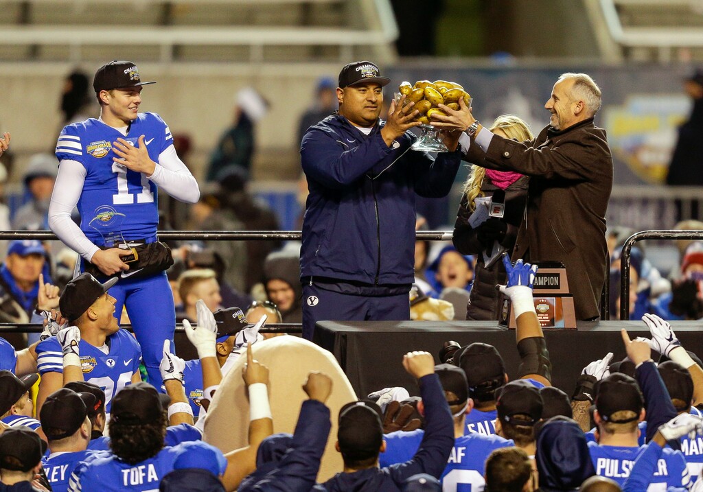 BYU coach Kalani Sitake receives the the trophy full of potatoes from Kevin McDonald, executive director of the Famous Idaho Potato Bowl, after BYU's 49-18 win over Western Michigan in the NCAA college football game Friday, Dec. 21, 2018, in Boise, Idaho. (AP Photo/Steve Conner)