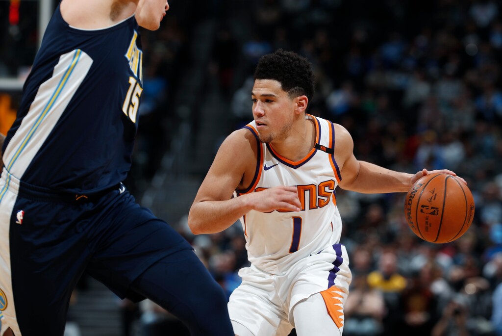 Phoenix Suns guard Devin Booker, right, drives the lane past Denver Nuggets center Nikola Jokic during the second half of an NBA basketball game Friday, Jan. 19, 2018, in Denver. Phoenix won 108-100. (AP Photo/David Zalubowski)