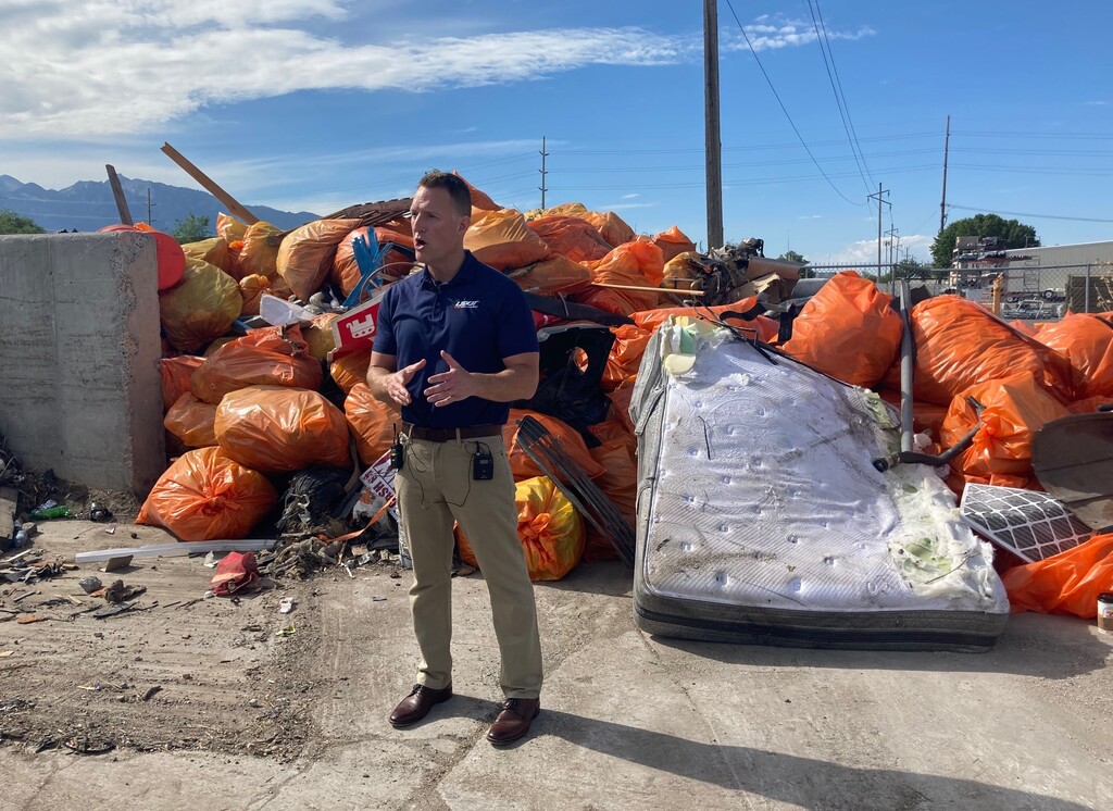 (Leia Larsen | The Salt Lake Tribune) Utah Department of Transportation spokesperson John Gleason stands Wednesday, June 30, 2021, near a large pile of trash crews collected off roads in Salt Lake County over the past month. The amount of time UDOT spends cleaning up litter and debris from the roads is up by 28% in the past five years.