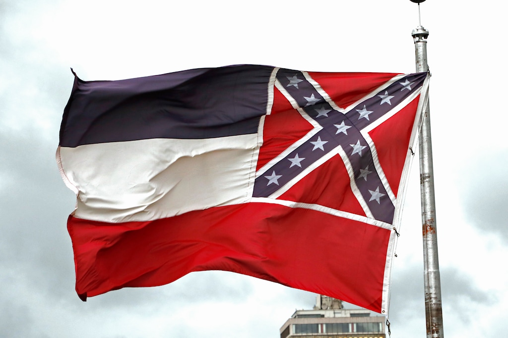 A Mississippi state flag flies outside the Capitol in Jackson, Miss., Thursday, June 25, 2020. Athletic coaches and their staffs from the state's public universities held a joint news conference and called for a change in the Mississippi state flag. Additionally several head coaches met with both the lieutenant governor and Speaker Philip Gunn, as well as their lawmakers, to lobby for the change. The current flag has in the canton portion of the banner the design of the Civil War-era Confederate battle flag, that has been the center of a long-simmering debate about its removal or replacement. (AP Photo/Rogelio V. Solis)