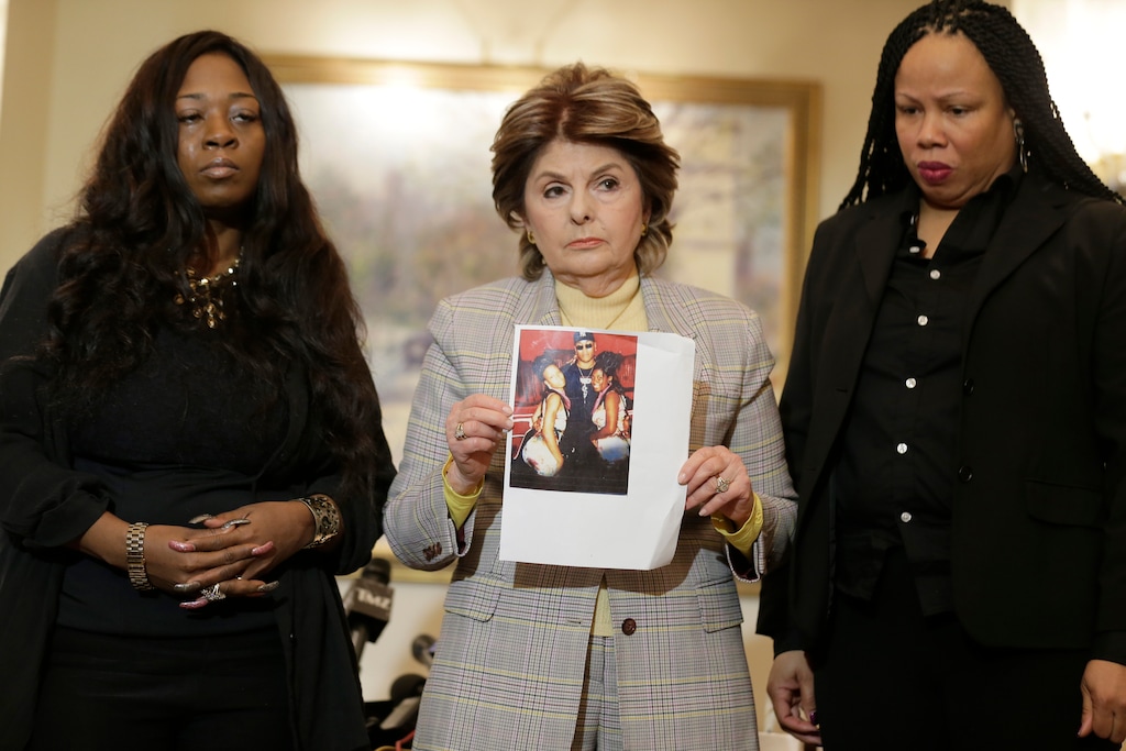As Latresa Scaff, right, and Rochelle Washington, left, look on as attorney Gloria Allred holds up a picture of them as teenagers on the night they claim they became victims of musician R. Kelly's sexual advances during a news conference in New York, Thursday, Feb. 21, 2019. Scaff and Washington are accusing musician R. Kelly of sexual misconduct on the night they attended a concert of his while they were teenagers.(AP Photo/Seth Wenig)