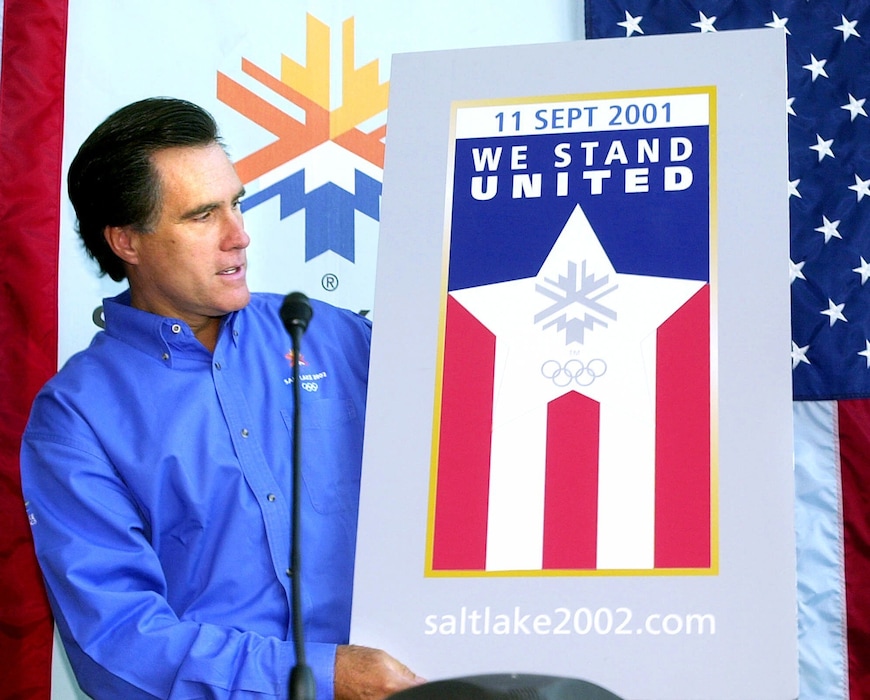 (Douglas Pizac | AP file photo) Mitt Romney, then president of the Salt Lake Organizing Committee, unveils the Olympic "We Stand United" pin during a news conference on Sept. 17, 2001 — shortly after the 9/11 terrorist attacks. Romney, now a U.S. senator from Utah, is urging Tokyo to go forward with plans to hold the summer games despite the pandemic.